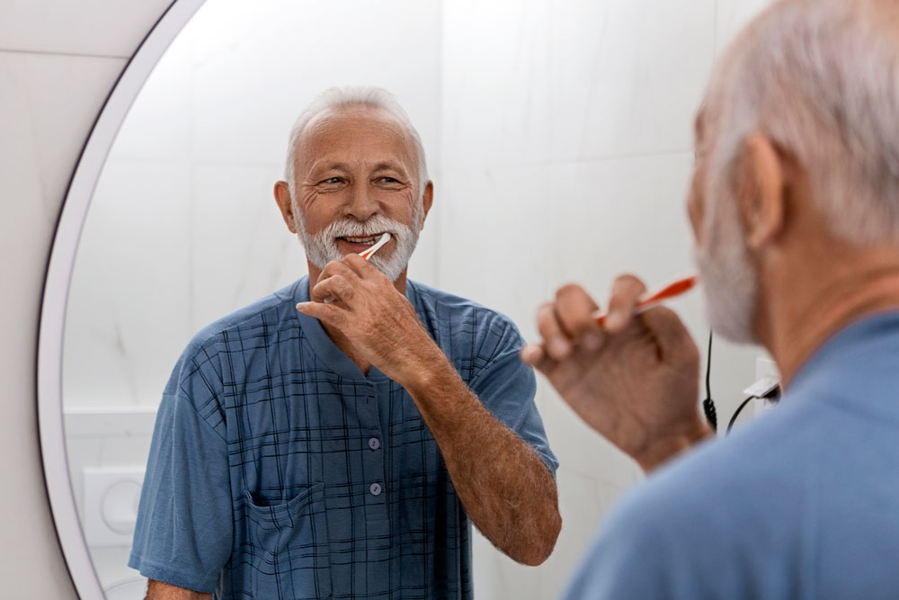 Bearded senior man smiling while brushing his teeth